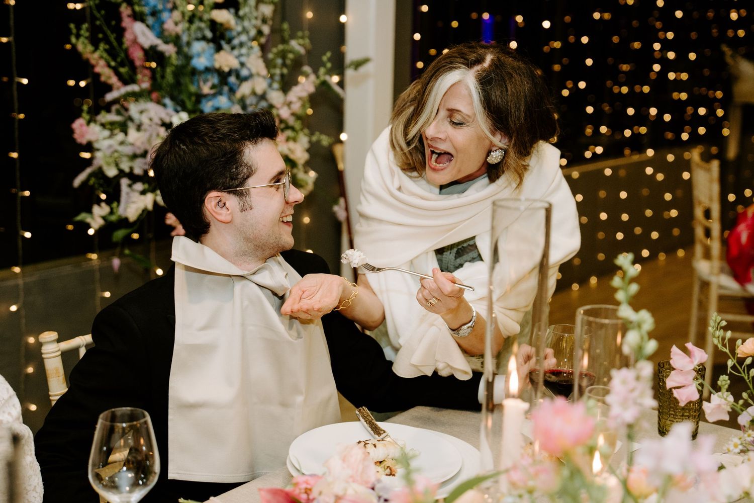 Wedding reception venue decorated with twinkling string lights and floral centerpieces on elegant dining tables.