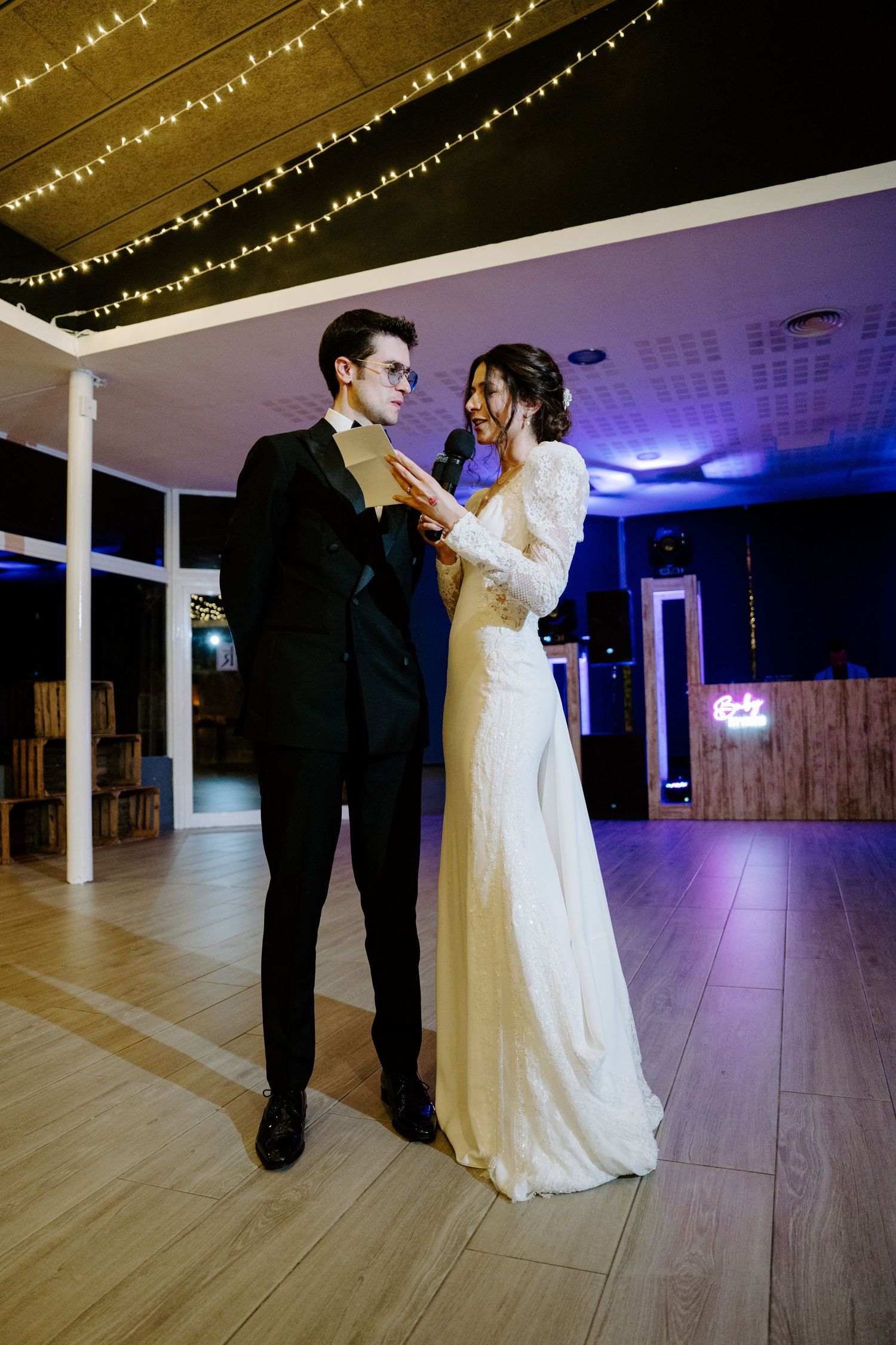 Wedding couple dancing in an elegantly lit reception hall with string lights overhead.