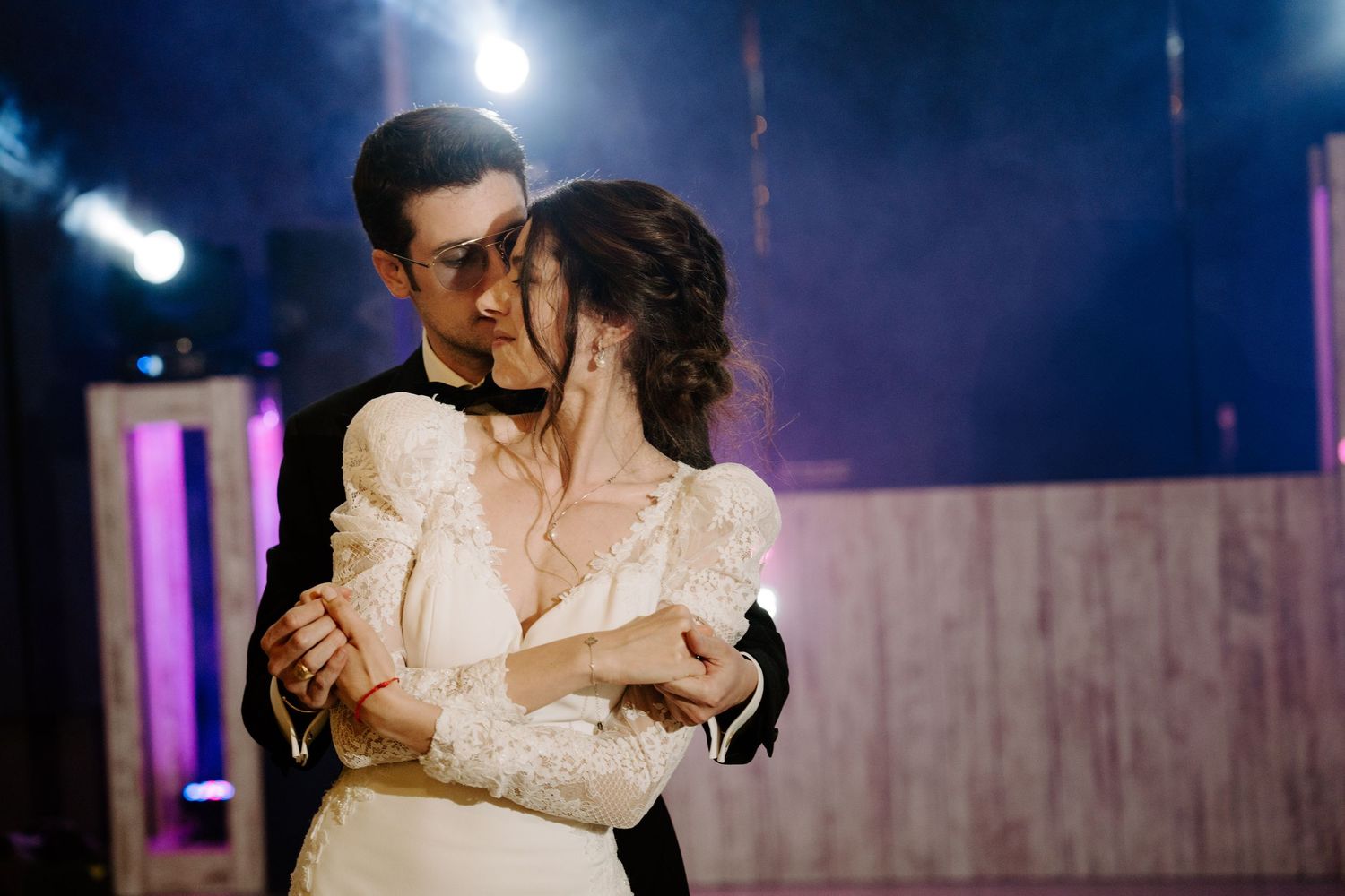 A romantic dance dip captured under dramatic blue spotlights on a dance floor.