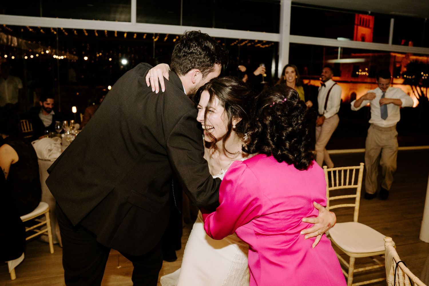 Wedding reception dance floor with guests dancing under warm outdoor lighting.