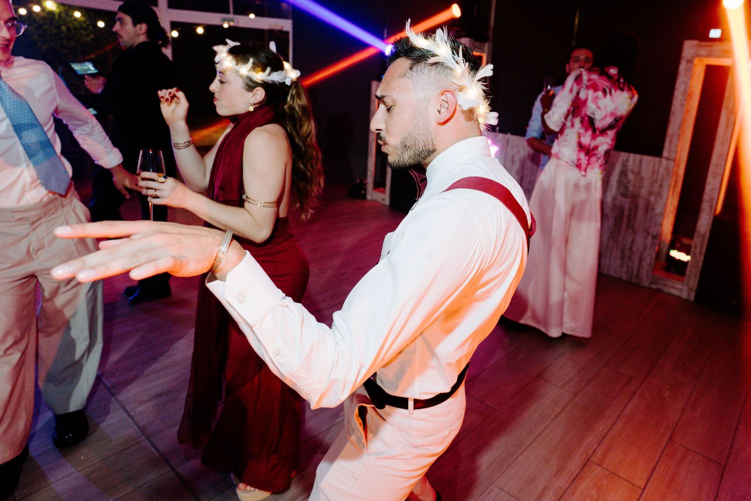 Energetic dance party scene with colorful lighting and people dancing in formal attire.