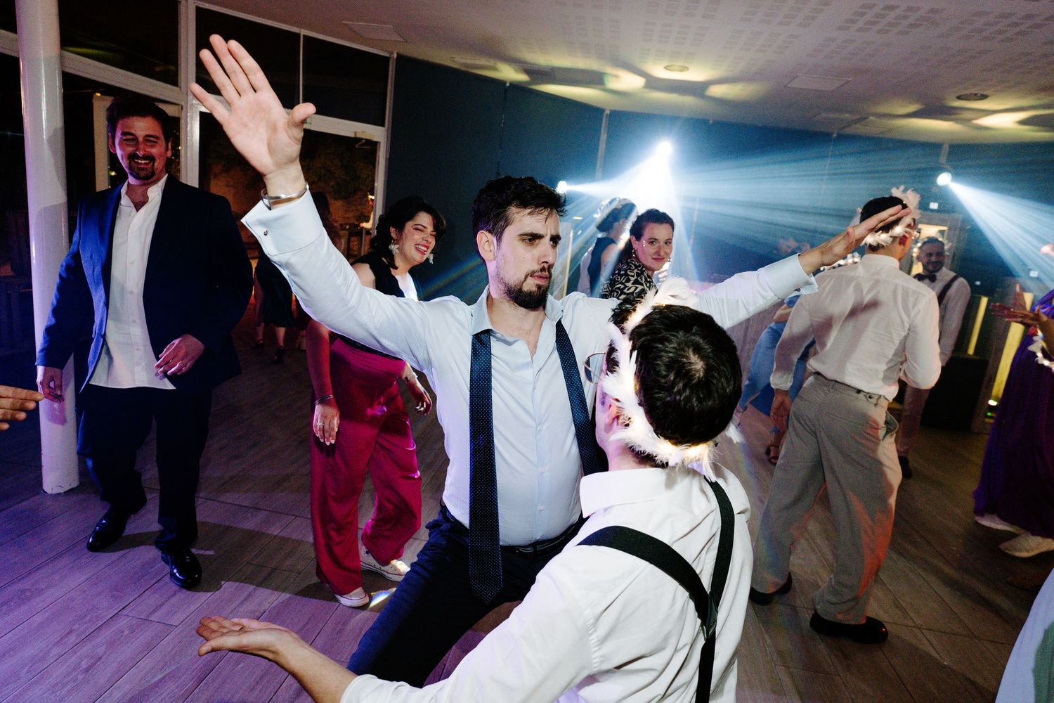 Lively reception dance floor with guests celebrating under atmospheric lighting.