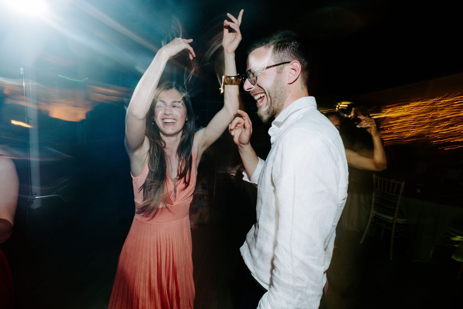 Party guests dancing and celebrating under moody blue and green lighting effects.