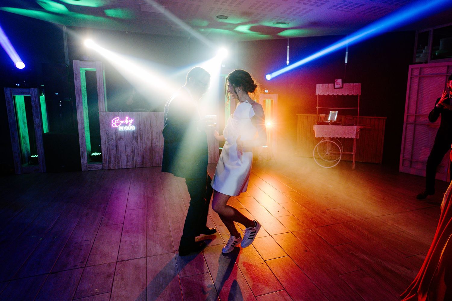 Dance floor illuminated with dramatic multicolored lighting beams creating a club-like atmosphere.