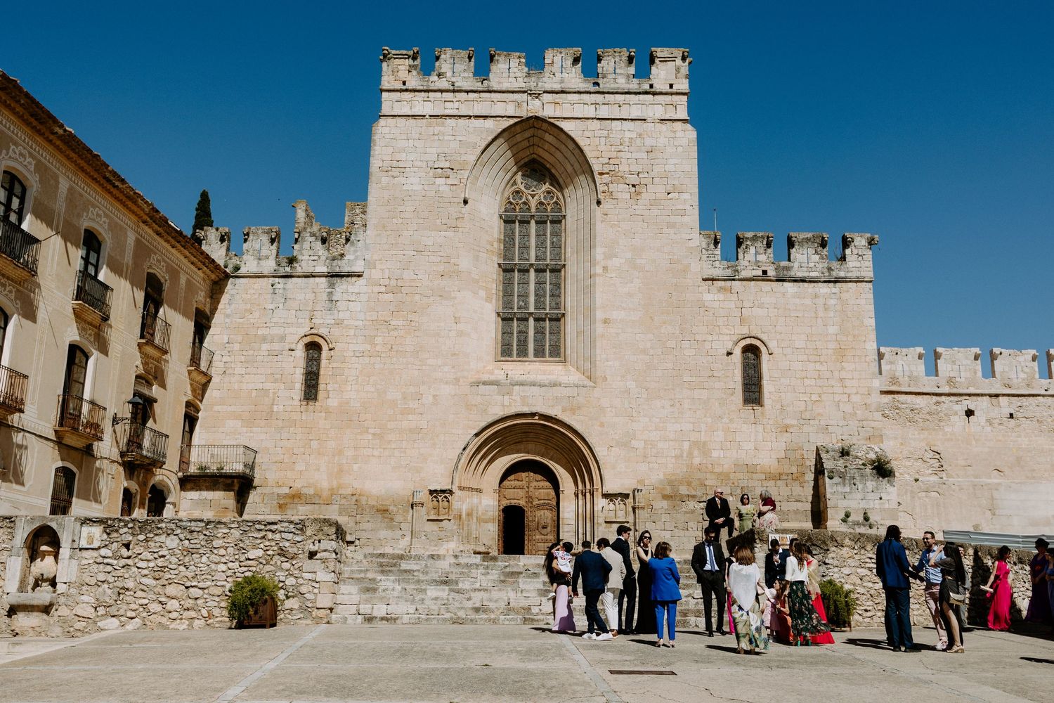 Medieval castle courtyard with stone walls and battlements against clear blue sky.