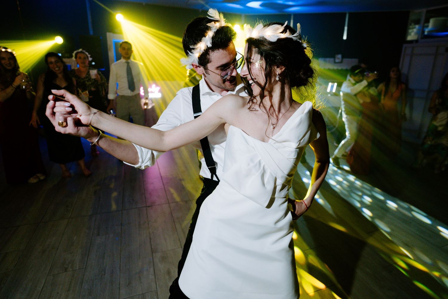 Wedding party dancing under vibrant yellow and green spotlights.