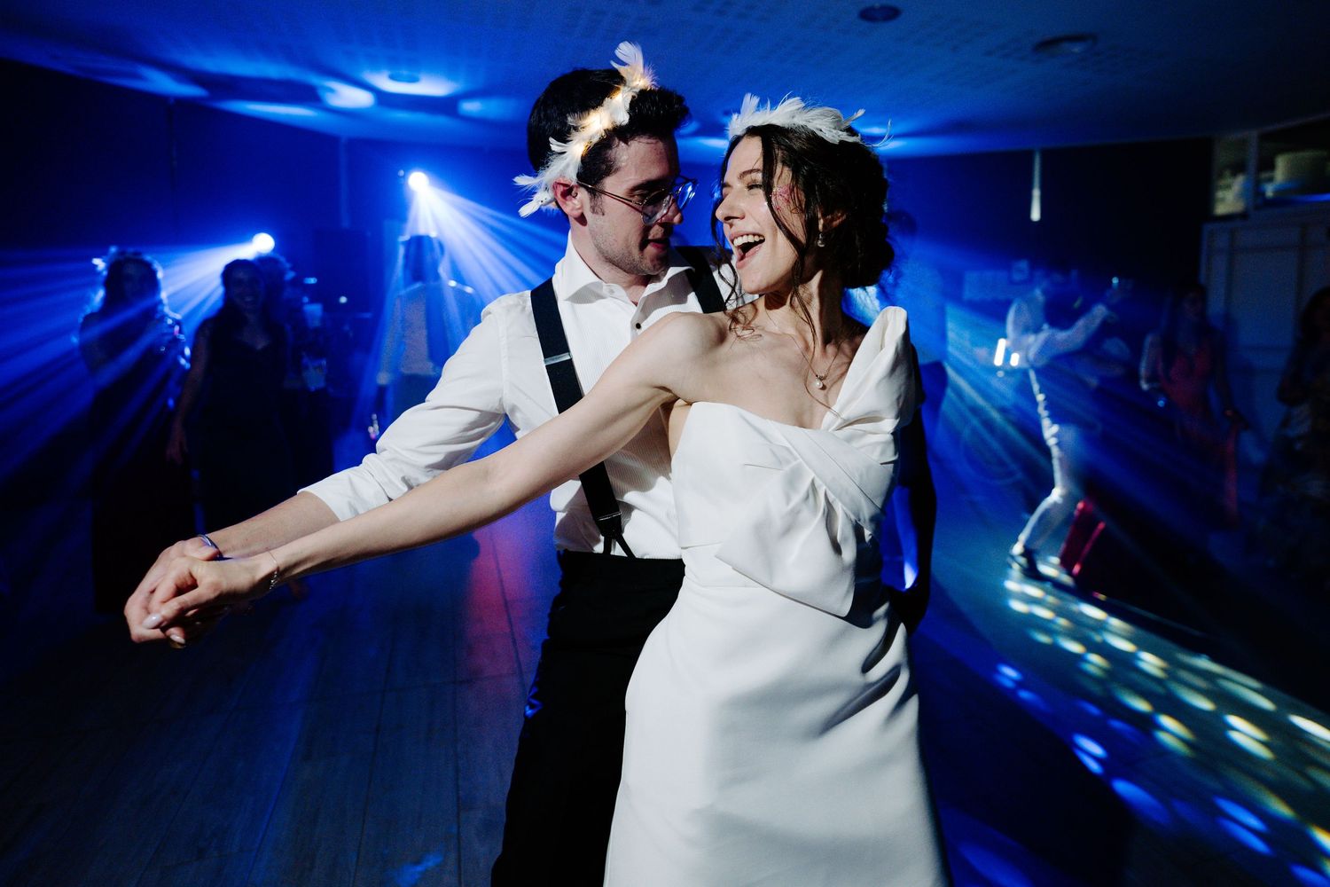 Wedding celebration on dance floor with dramatic blue lighting and dynamic movement.