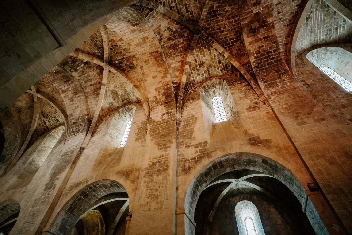 Ancient vaulted stone ceiling with dramatic lighting and arched architectural details.