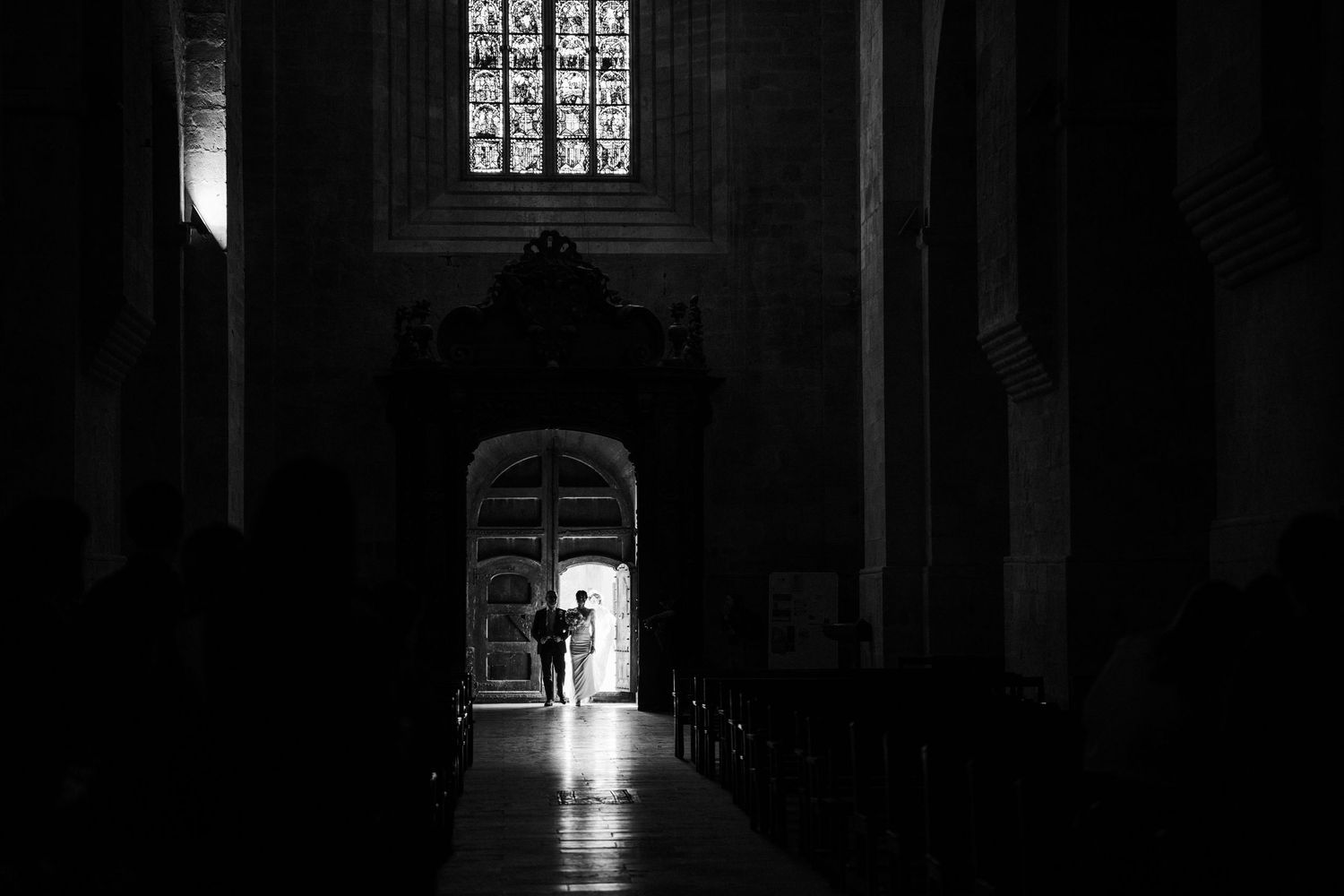 Dark church interior with dramatic light streaming through stained glass windows.