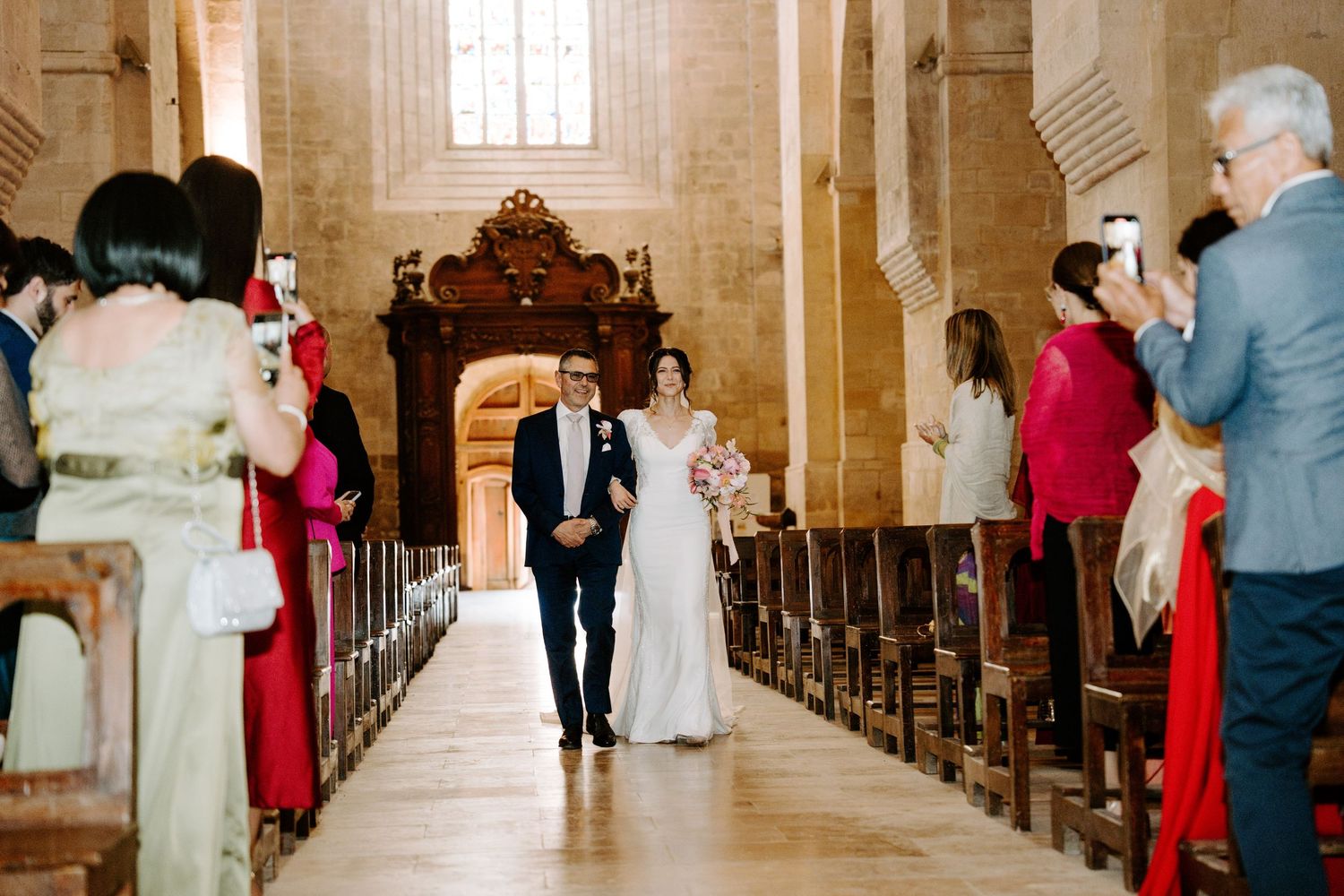Wedding guests line the church pews as a couple stands at the altar during their ceremony.