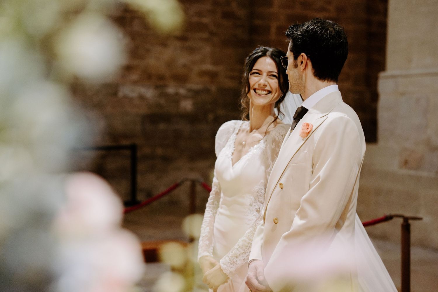 A couple shares a tender moment during their wedding ceremony in an ornate church setting.