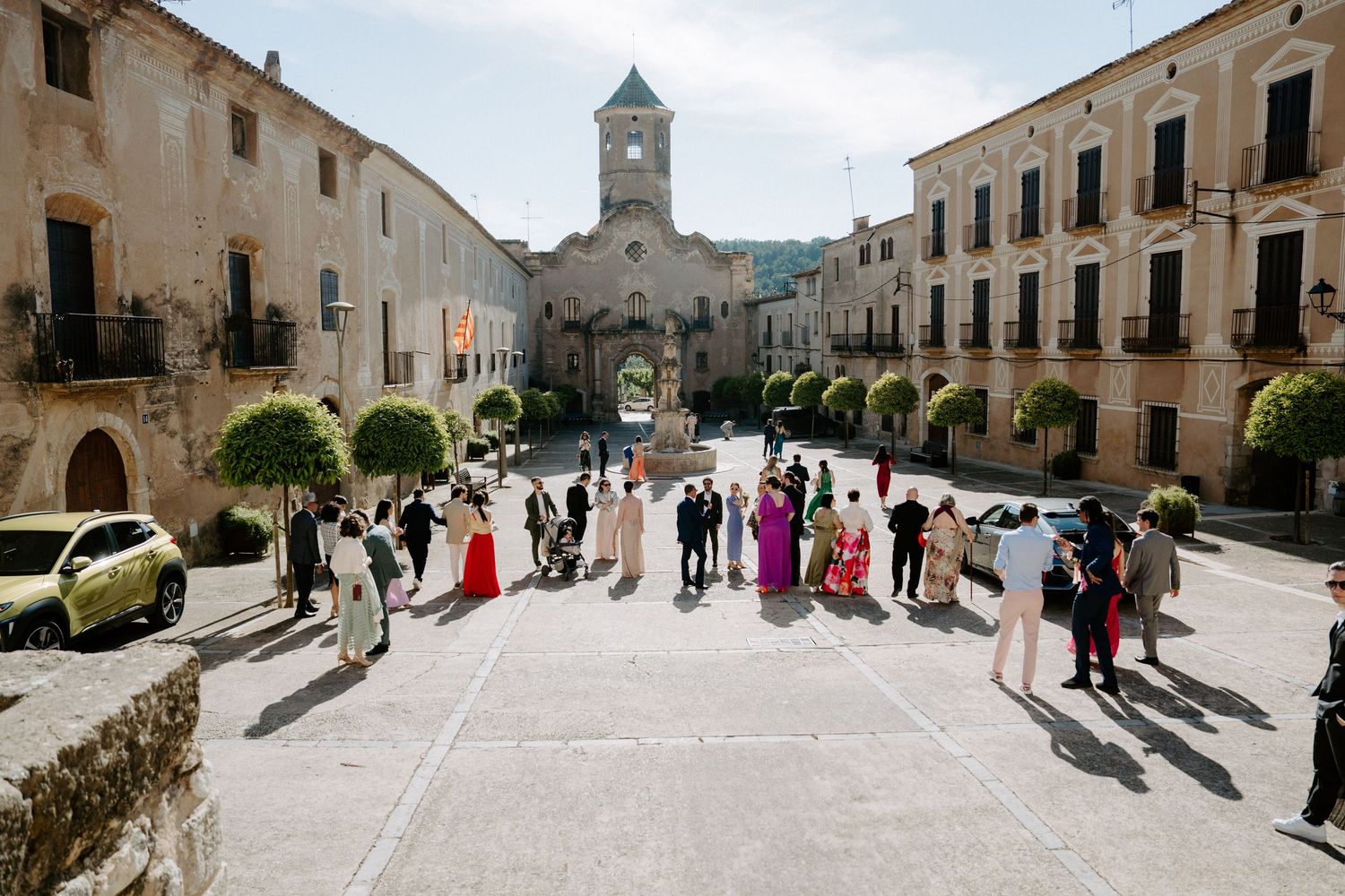 Panoramic view of historic town square with stone buildings and church tower.