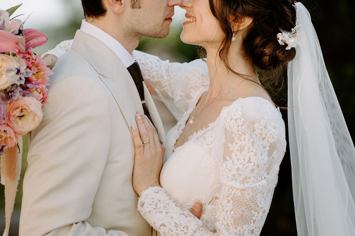 Romantic wedding couple sharing intimate moment in lace dress and light suit.