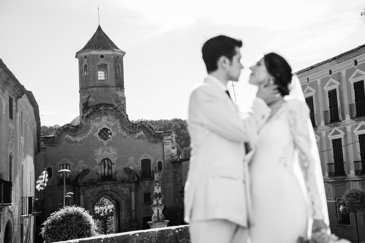 Black and white panorama of church courtyard with wedding couple.