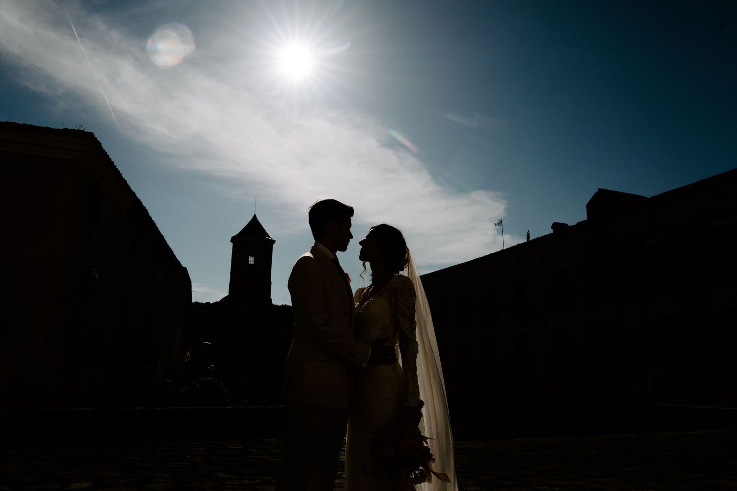 Dramatic silhouette of church architecture against bright sky.