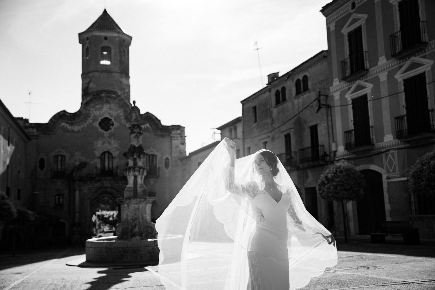 A silhouetted bride spins her dress against a dramatic church backdrop.