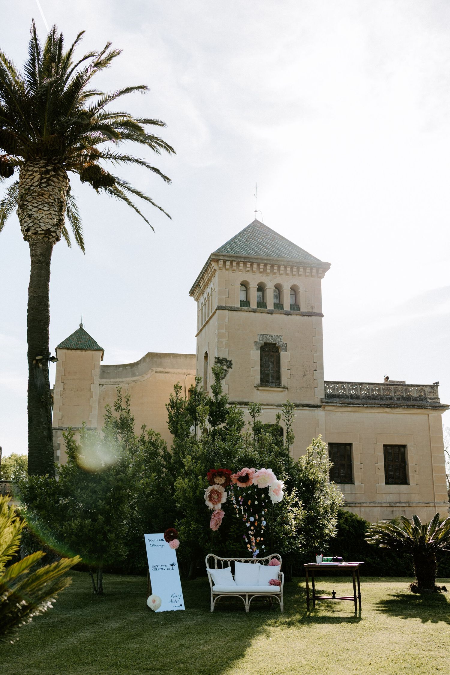 White Mediterranean-style villa with palm trees and landscaped gardens on a sunny day.