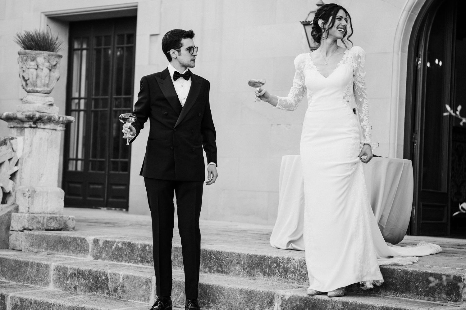 Black and white photo of newlyweds pouring champagne into a glass tower.