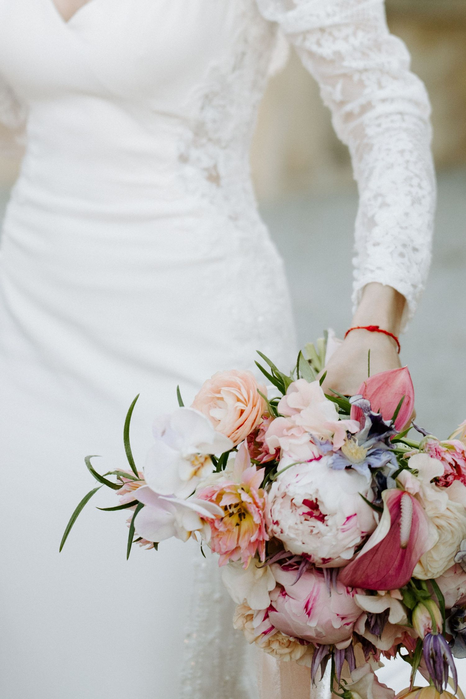 Delicate pink and white peony wedding bouquet with lace dress details.