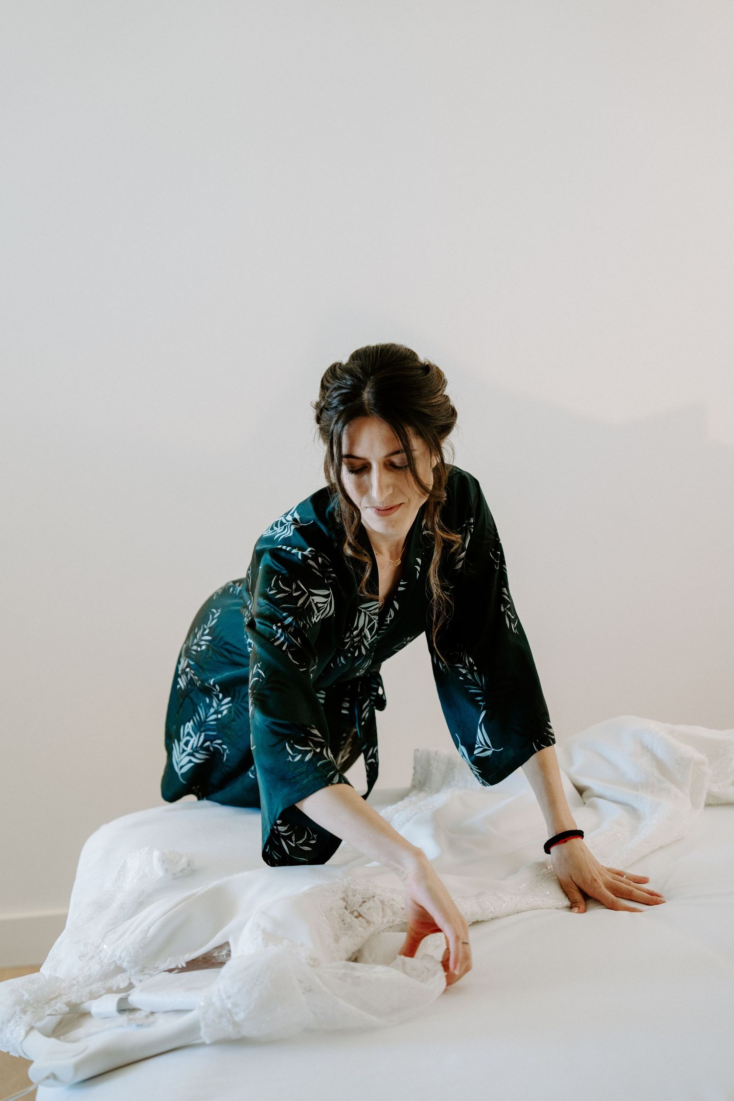 Woman in dark patterned kimono arranging white fabric on the floor.