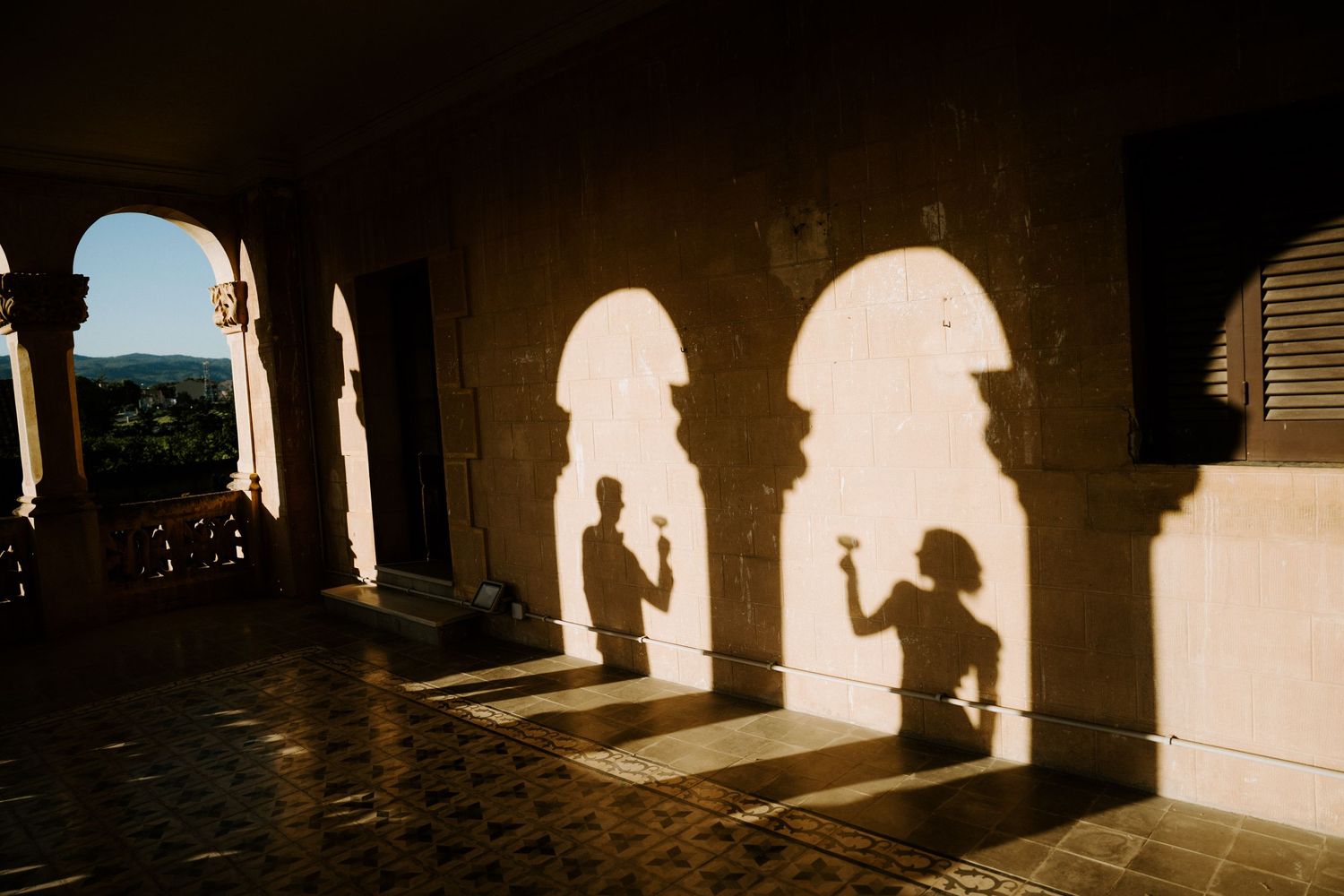 Silhouetted figures in dramatic lighting create romantic shadows along colonnade.
