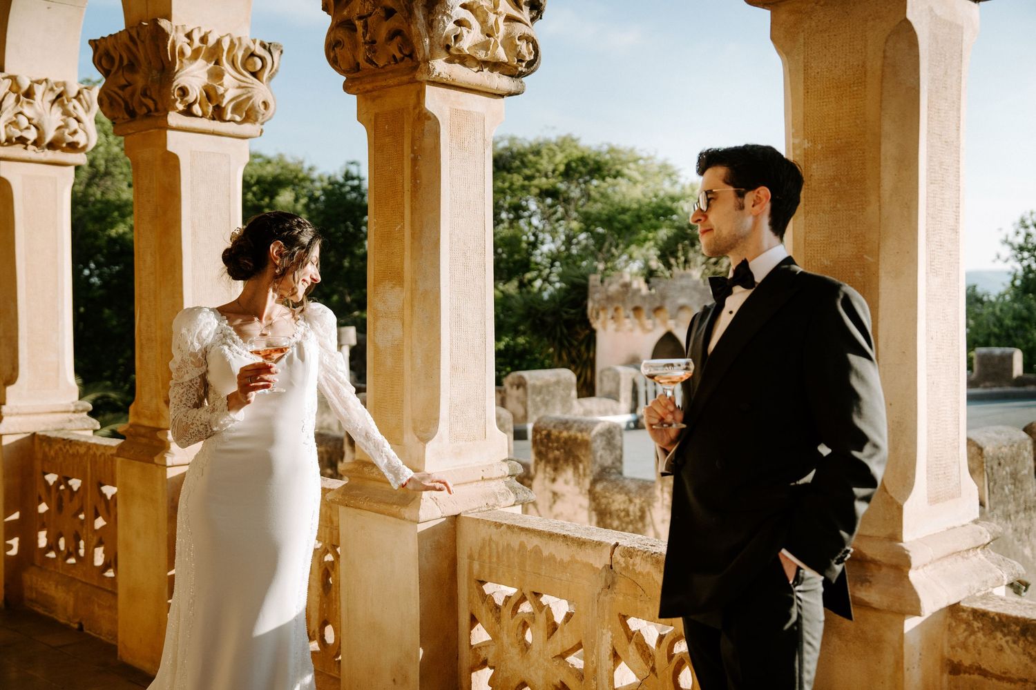 Wedding couple photographed between classical stone columns with ornate capitals.