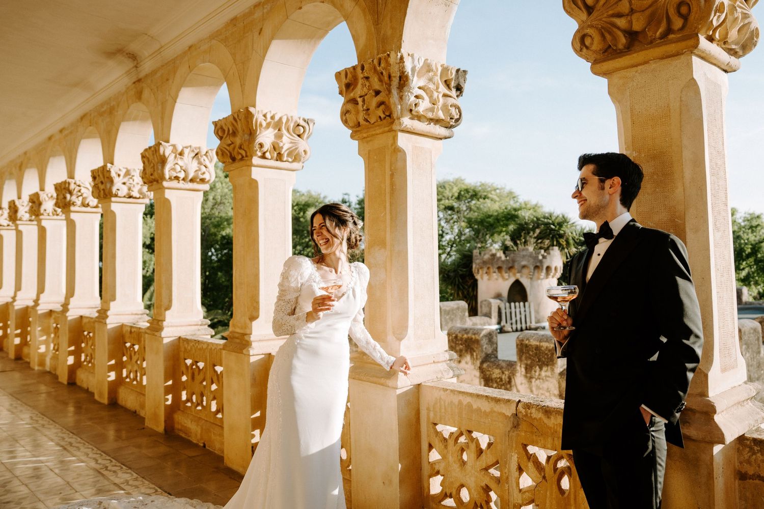 Sun-drenched architectural colonnade provides romantic setting for wedding portraits.