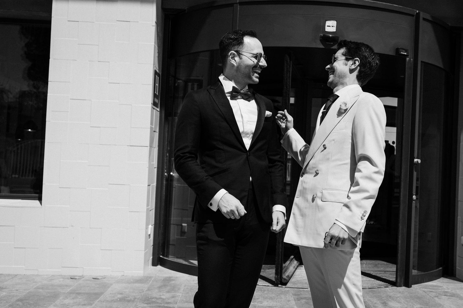 People in formal attire walking and conversing outside a modern building.