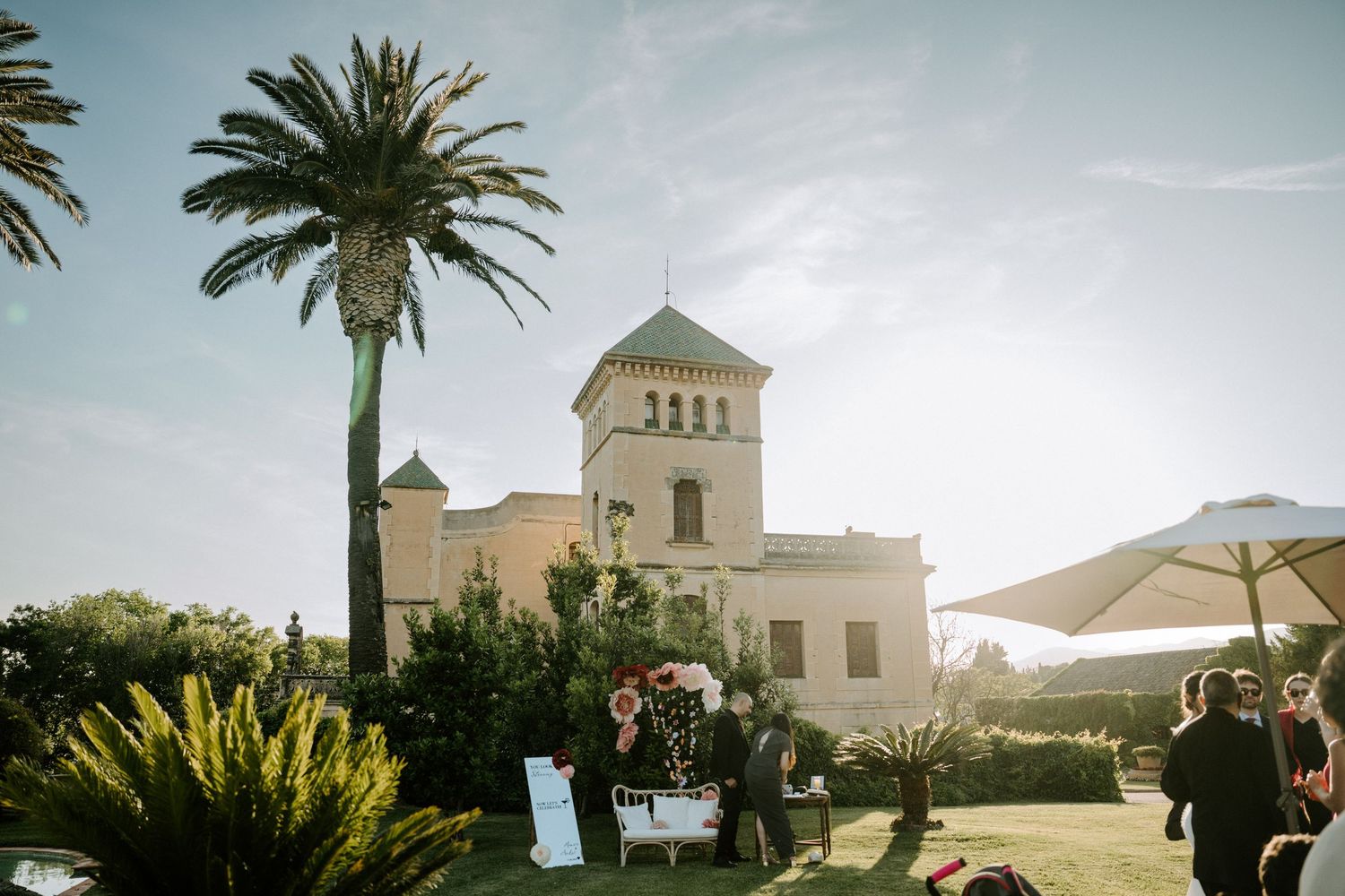 Mediterranean style wedding venue with palm trees and white architecture against blue sky.