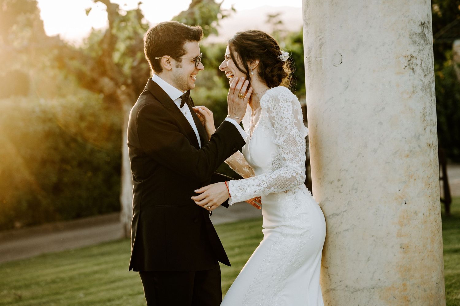 A romantic sunset wedding portrait shows a couple embracing in golden light on a grassy lawn.
