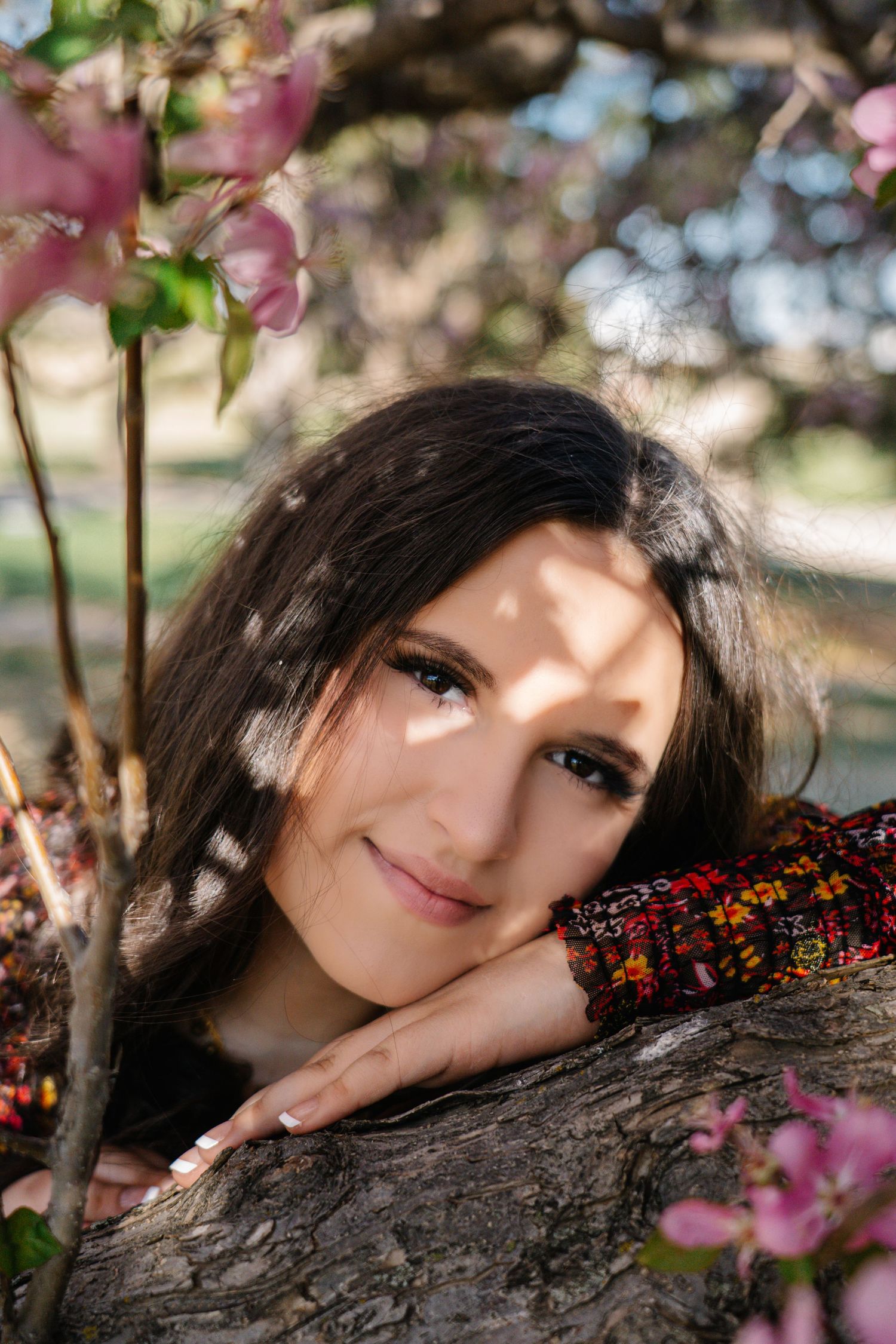 A portrait in nature with pink spring blossoms and soft bokeh lighting creating a dreamy atmosphere.