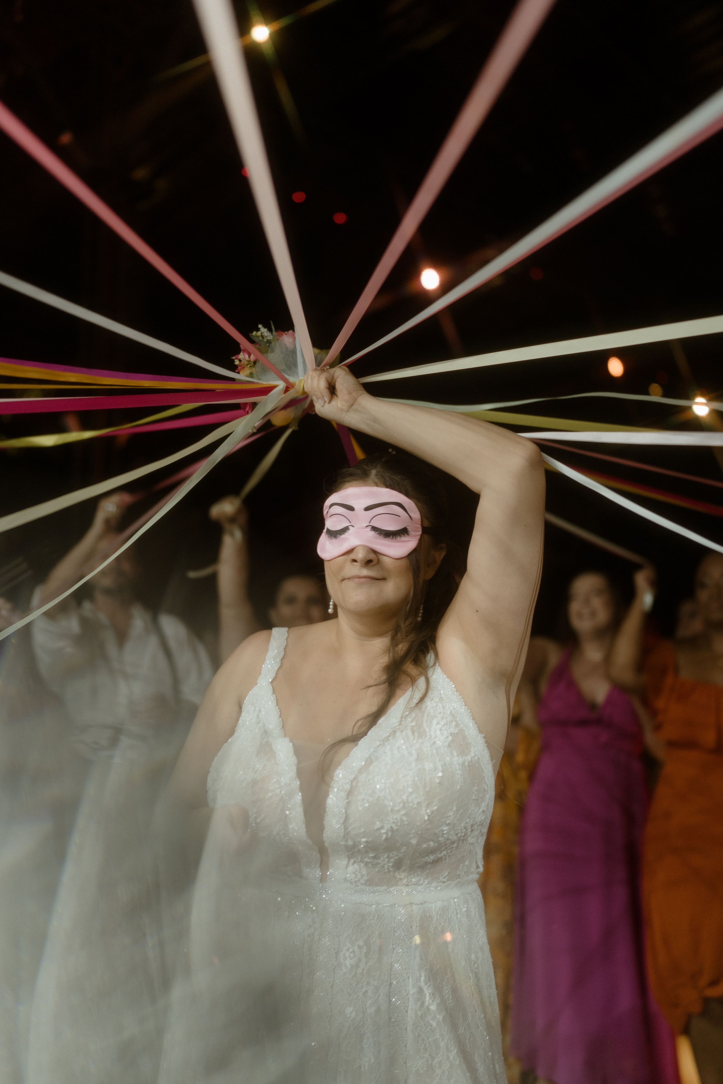 Person in white dress holding colorful ribbons during celebration with dramatic lighting effects.