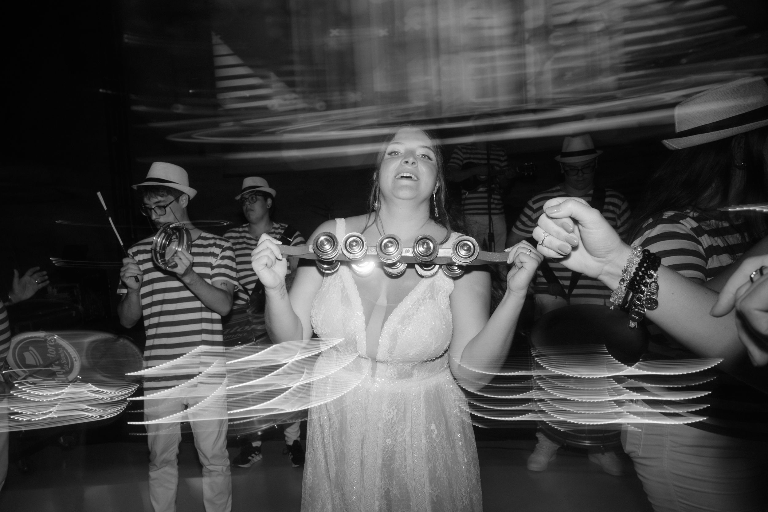 Long exposure black and white photograph of dancers creating light trails on stage.