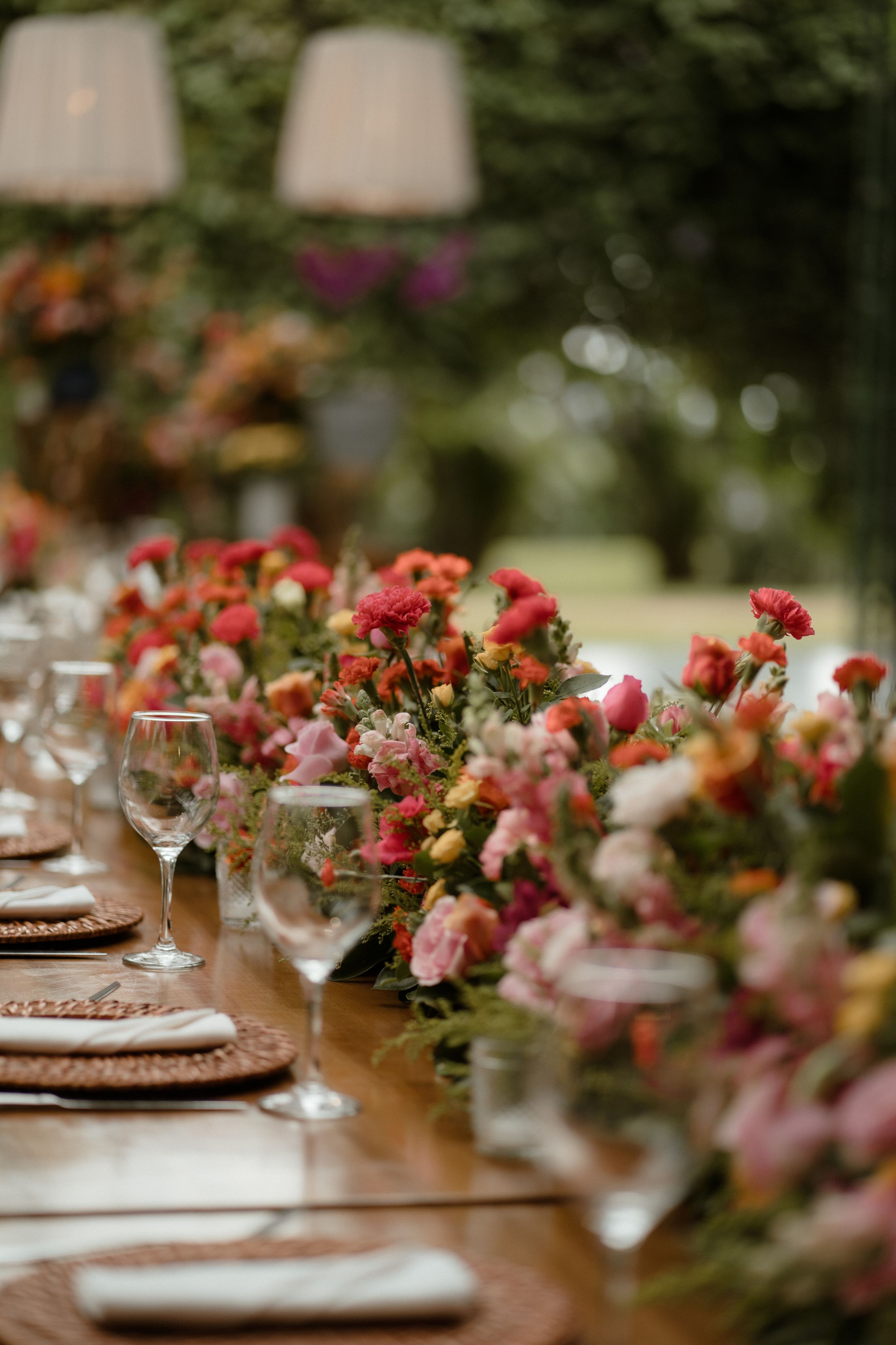 Wedding table decorations with pink and red floral arrangements and formal place settings.