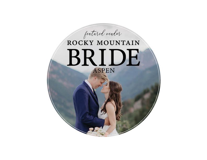A circular wedding logo design featuring a couple embracing in front of the Rocky Mountains in Aspen.