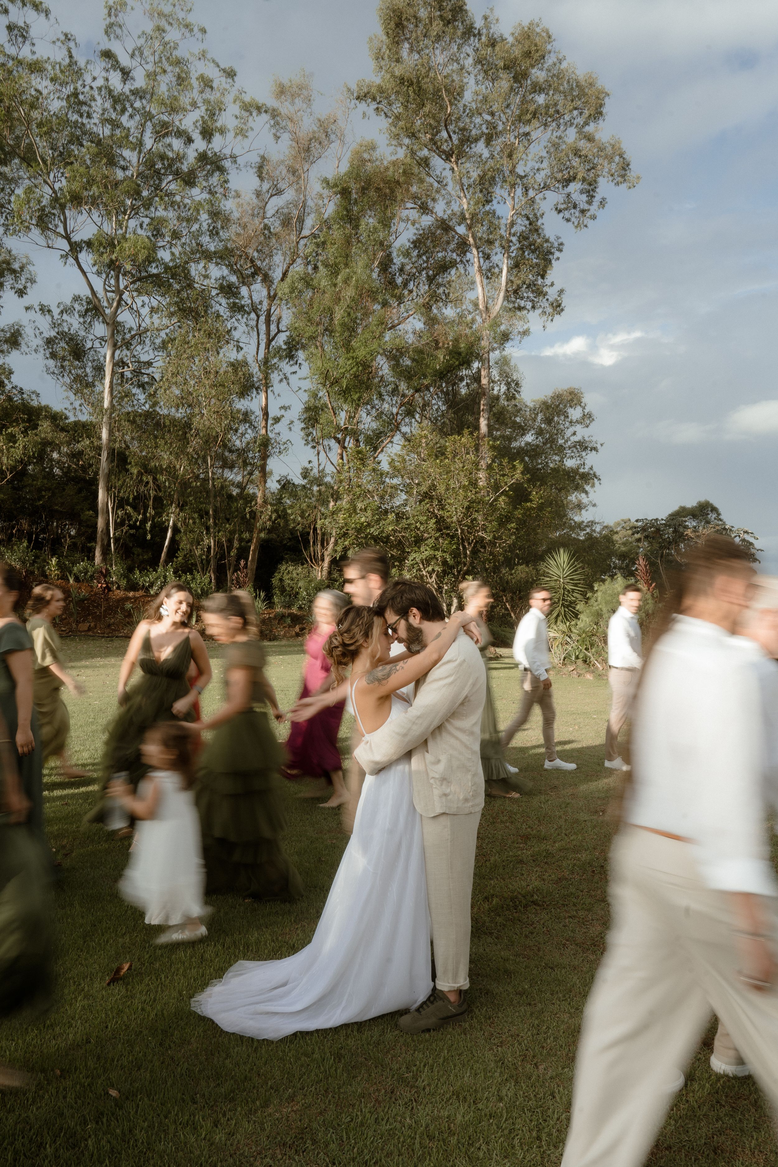 Wedding celebration on a grassy lawn with tall eucalyptus trees in the background at golden hour.