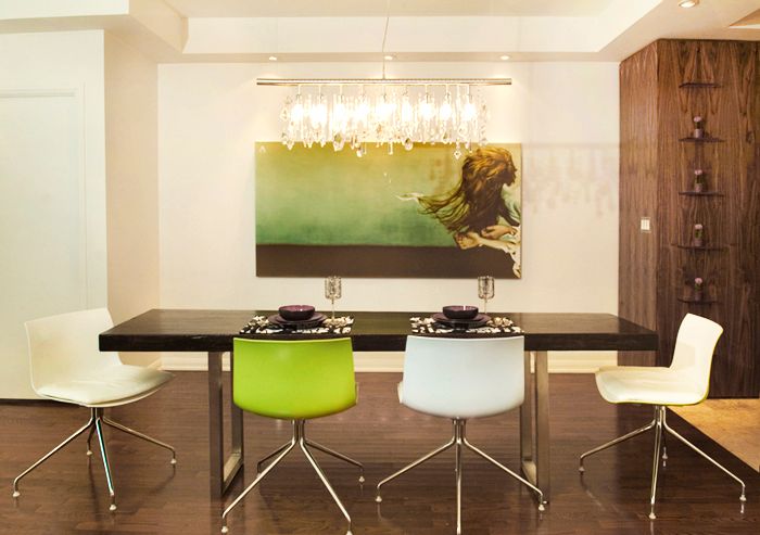 Modern dining room with crystal chandelier, lime green chairs and artwork depicting fast moving object against green wall.