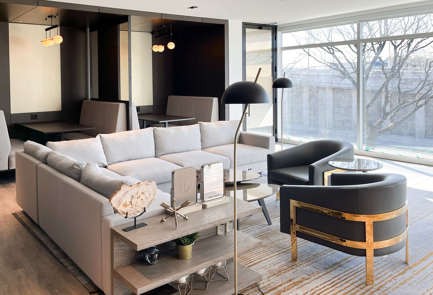 Modern living room features a plush gray sectional sofa, stylish accent chair, and large windows overlooking winter scenery.