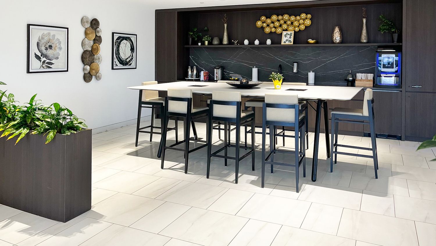 Modern dark kitchen with island bar seating, white floors and yellow pendant lights showcasing a sleek contemporary design.