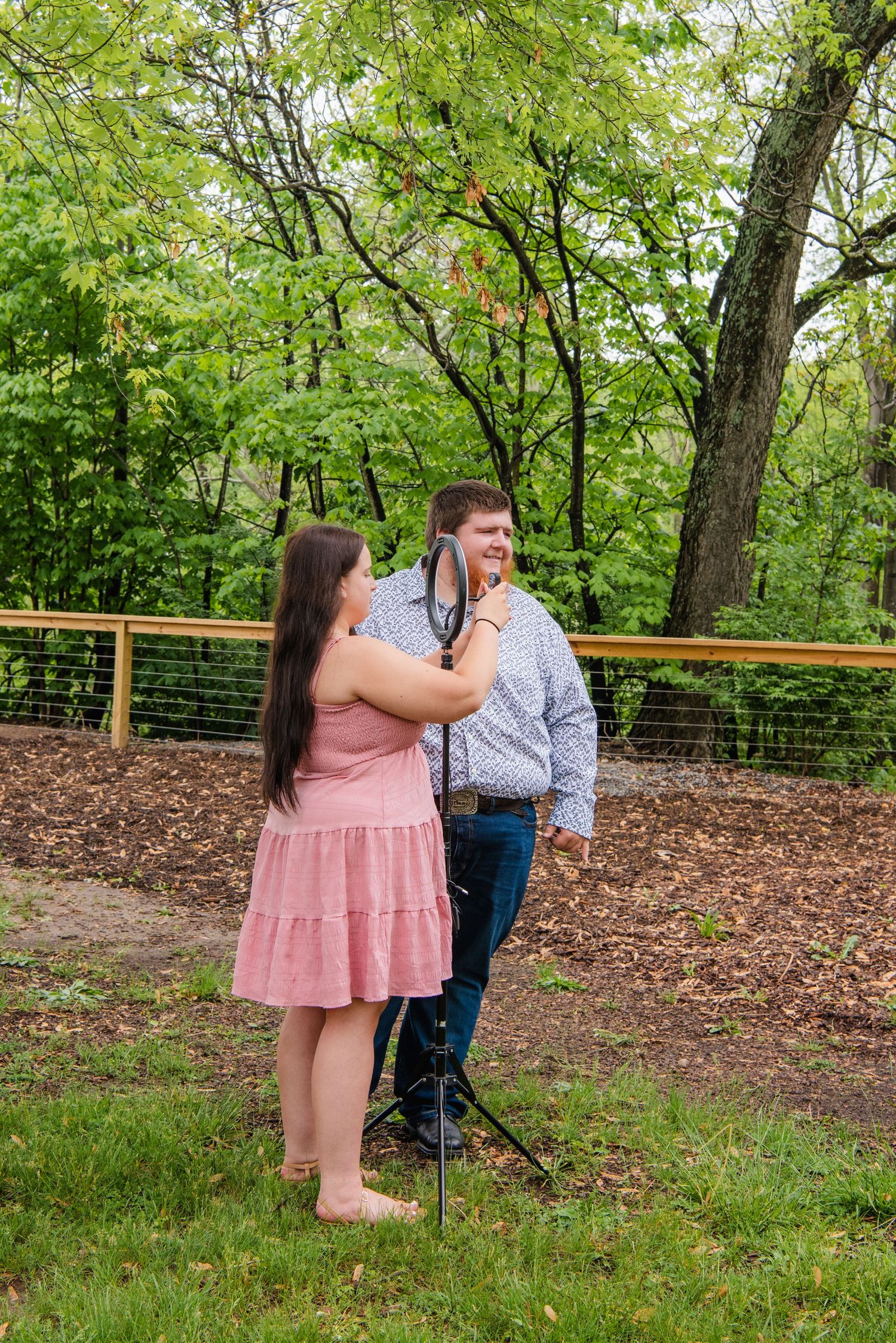 A couple shares an intimate moment on a deck surrounded by spring foliage.