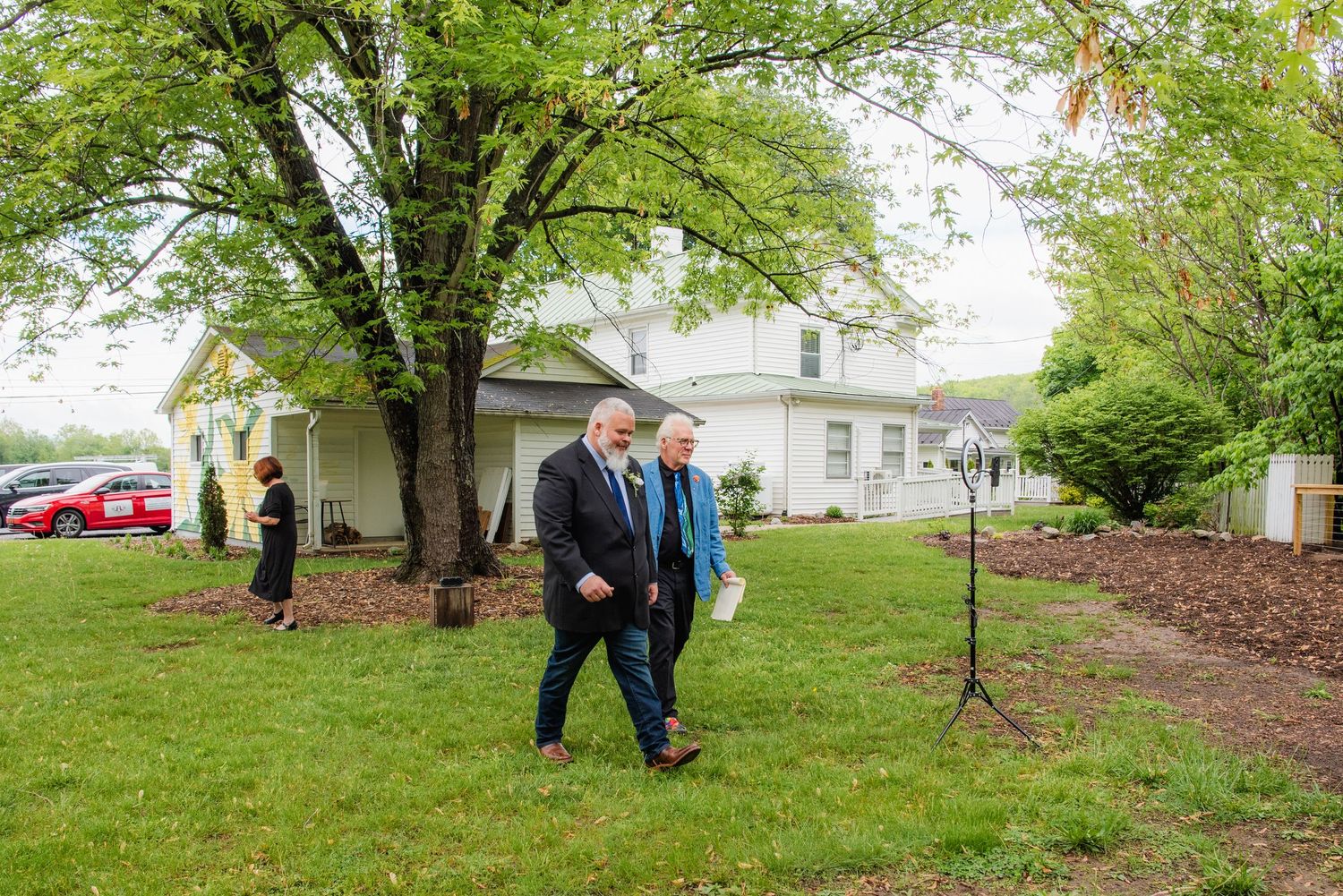 Two people walk across a grassy lawn outside a building on a cloudy day.
