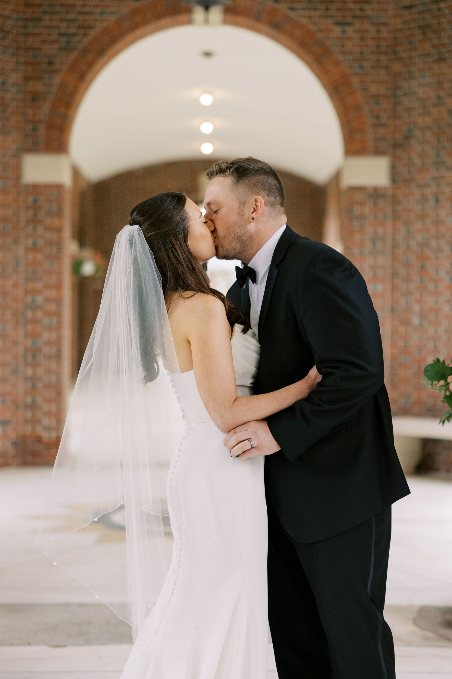 A romantic wedding moment shared under a brick archway at the Hall of Springs in Saratoga Springs, New York.