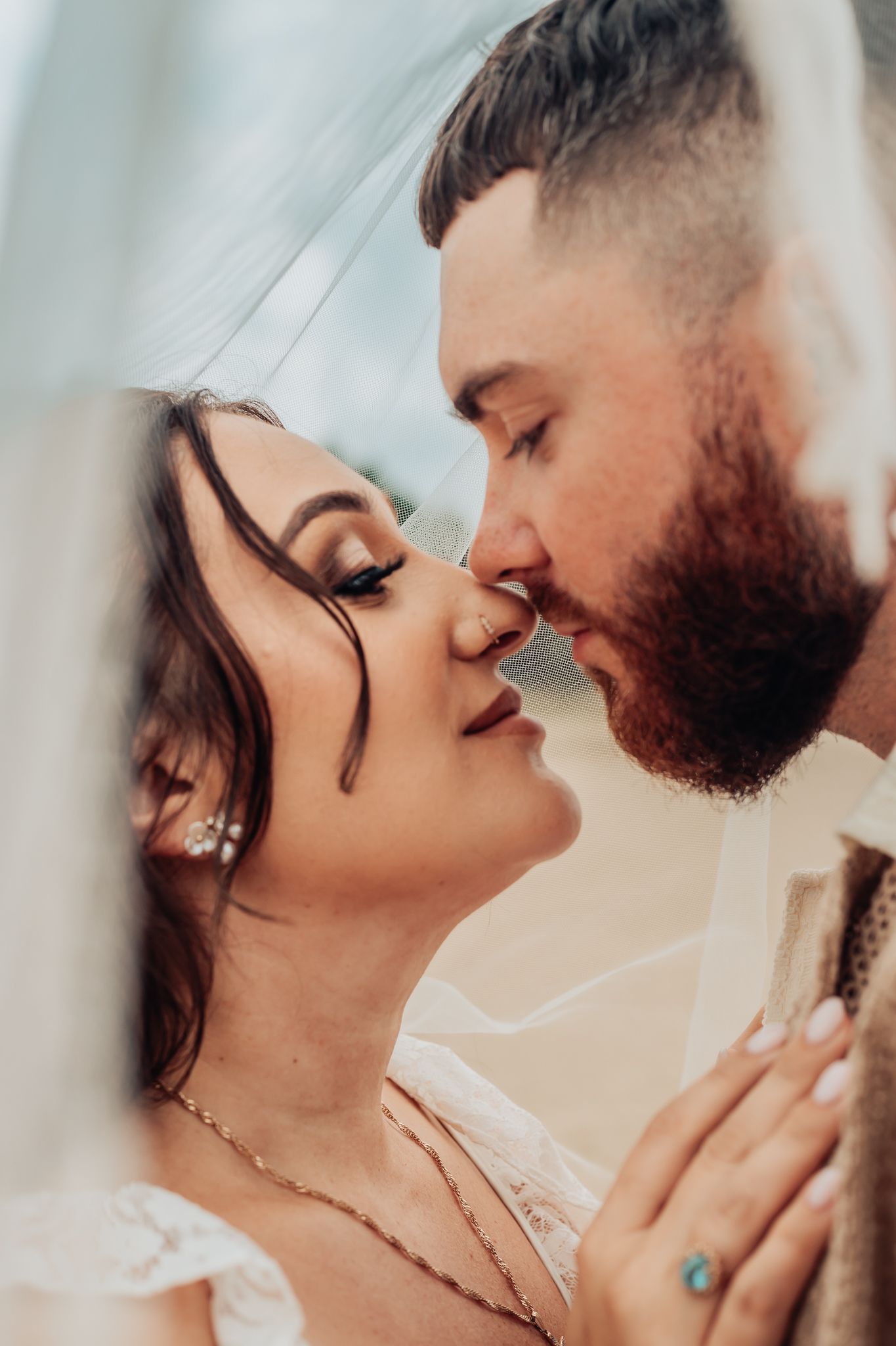 bride and groom under a veil at the sand dunes