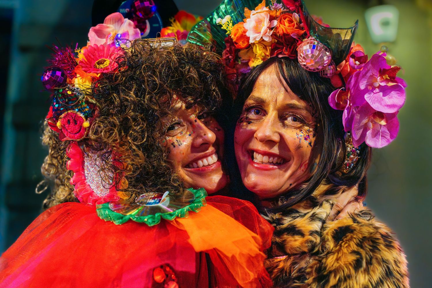 Two friends in colorful carnival costumes hugging and expressing authentic joy at an event. Vastelaovend in Venlo Vivitu