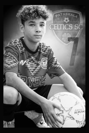 Black and white photo of a young soccer player in a Celtics SC jersey holding a ball with team logo visible in background.