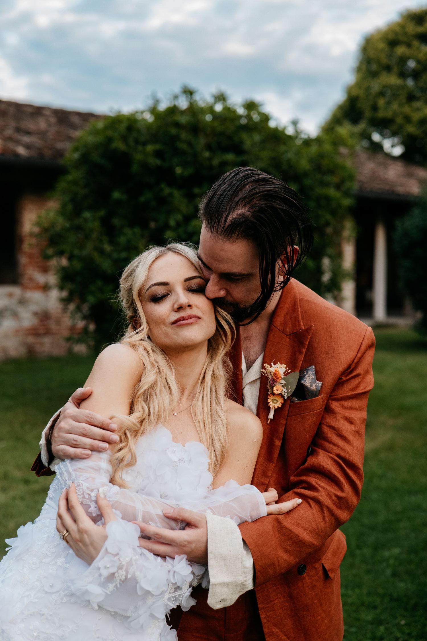 Newlyweds celebrating with guests during an outdoor ceremony under a stone archway.