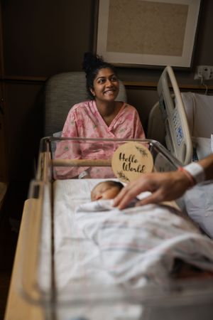 A joyful moment captured in a hospital room with a new mother and sleeping baby.