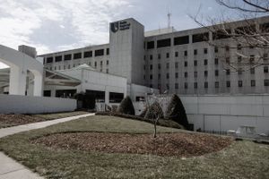 A modern multi-story hospital building with white exterior under cloudy skies.