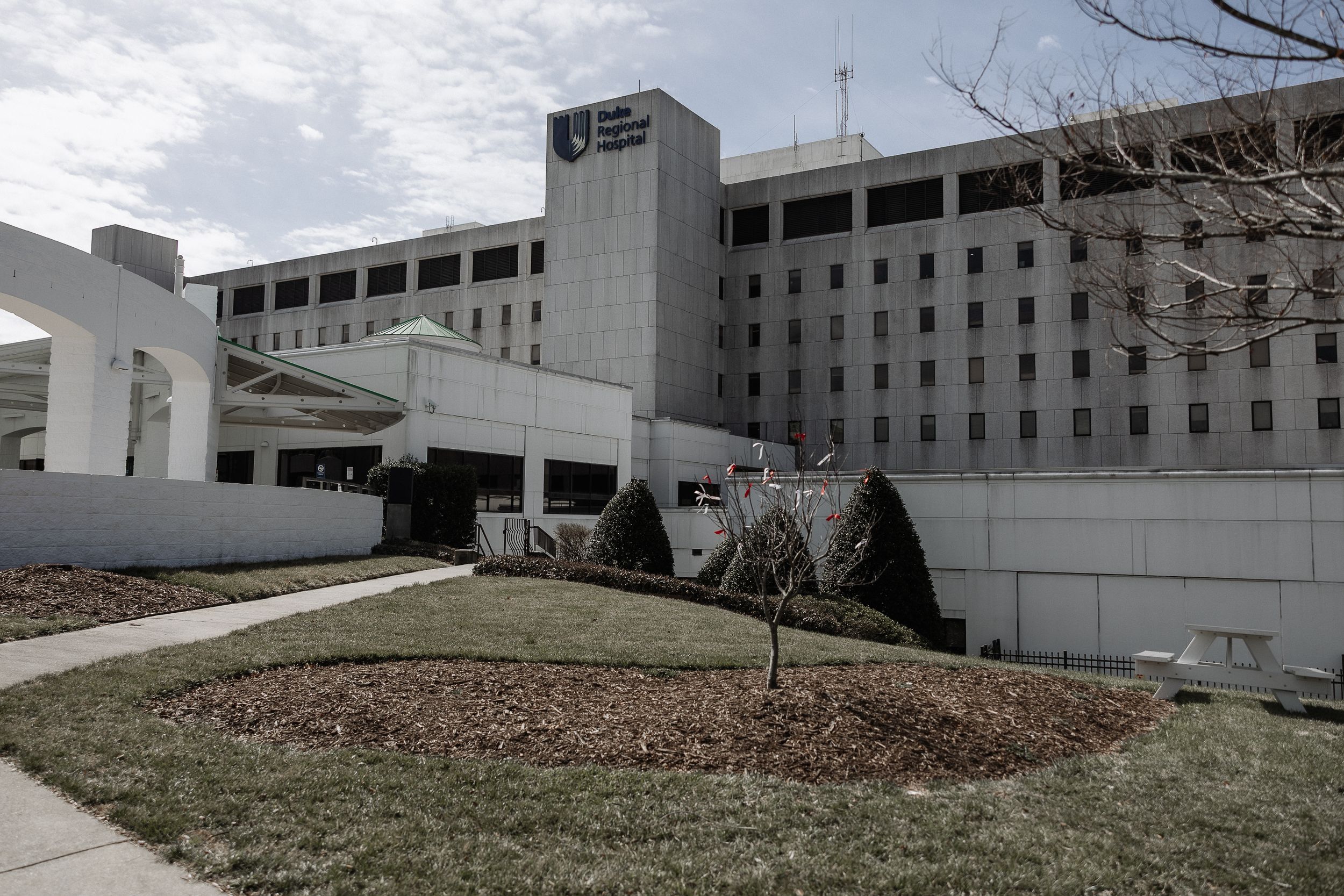A modern multi-story hospital building with white exterior under cloudy skies.