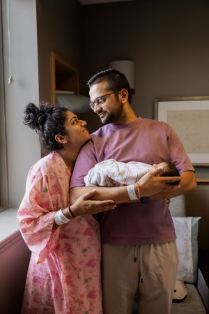 A tender moment as new parents gaze lovingly at their newborn baby in a hospital room.
